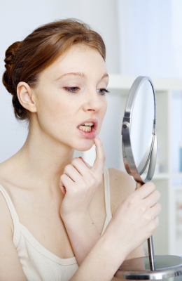 Young woman looking at her mouth in mirror